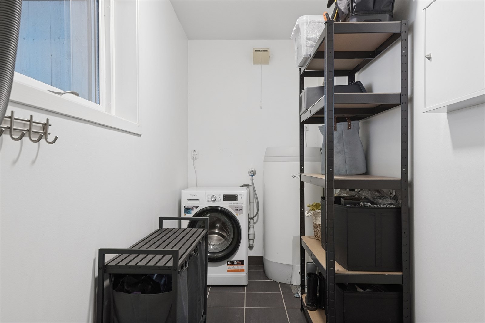 Vaskerommet har fliser på gulvet og malte plater på vegger, med opplegg for vaskemaskin og tekniske installasjoner. Galleribilde