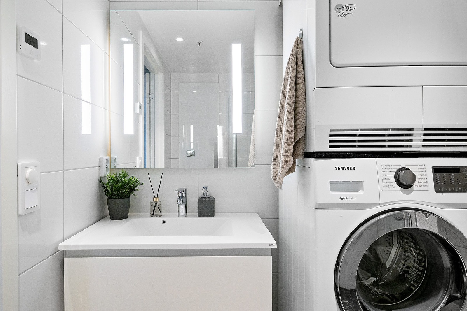 Badet har dusjhjørne med glassdører, vegghengt toalett og servant med speil og belysning. Det er opplegg for både vaskemaskin og tørketrommel. Galleribilde