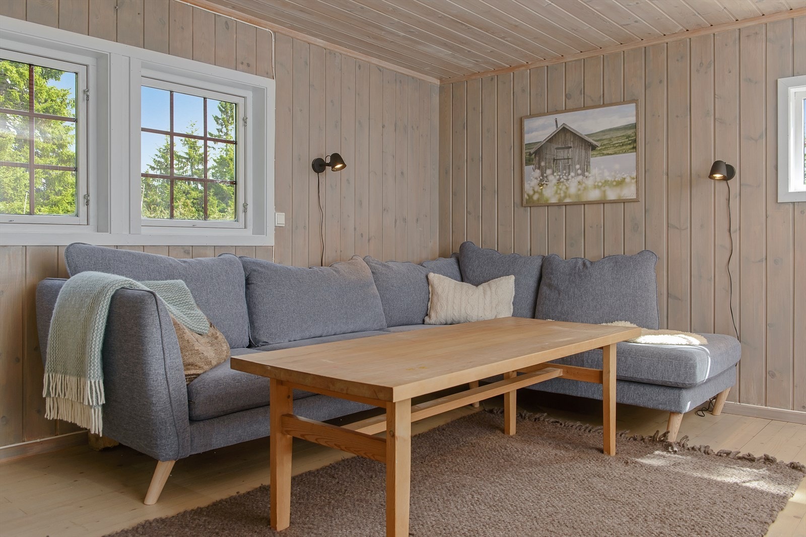 Koselig sofakrok under vinduet. Vegger og tak er beiset i en tidløs fargetone. Tregulvet er slipt og står fint til veggene. Galleribilde