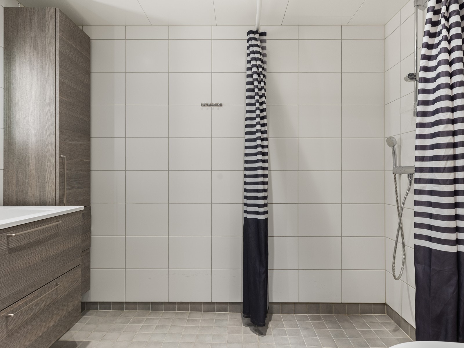 Badet har innredning med servant, vegg hengt toalett og dusjhjørne med glassdører Galleribilde