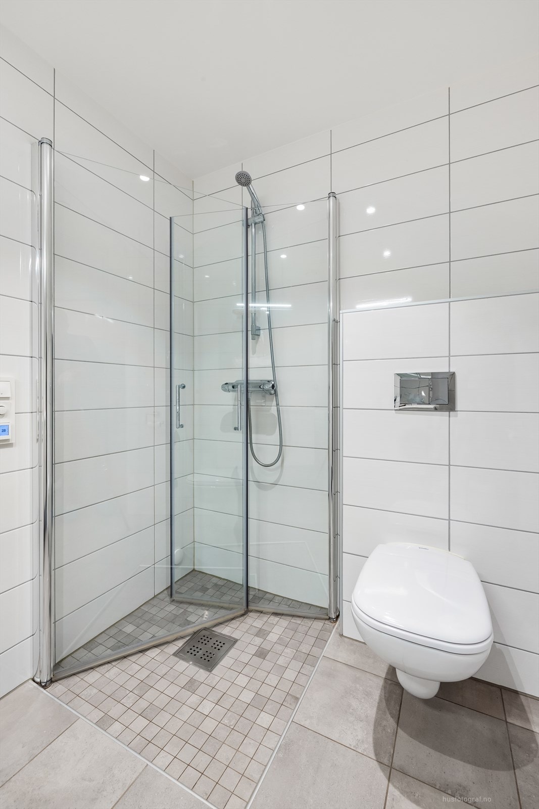 Badet har vegghengt toalett og dusjhjørne med foldedører i glass. Galleribilde