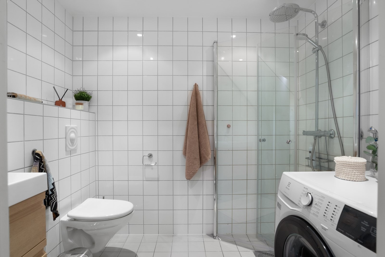 Dusjhjørnet med innfellbare dører i herdet glass og praktisk opplegg for vaskemaskin. Galleribilde