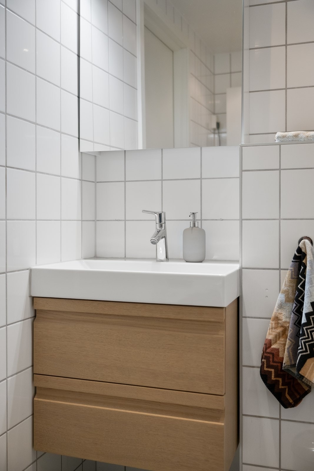 Baderomsinnredning med glatte fronter og veggskap med speilfronter over servanten. Galleribilde