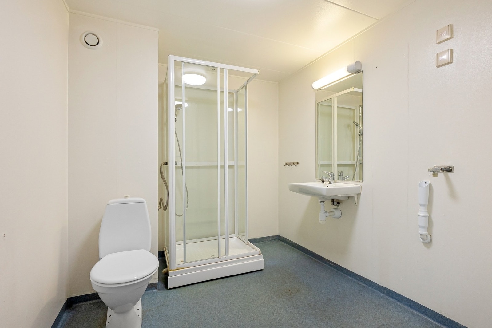 Romslig bad med linoleumsgulv, gulvstående wc, dusjkabinett og speil Galleribilde