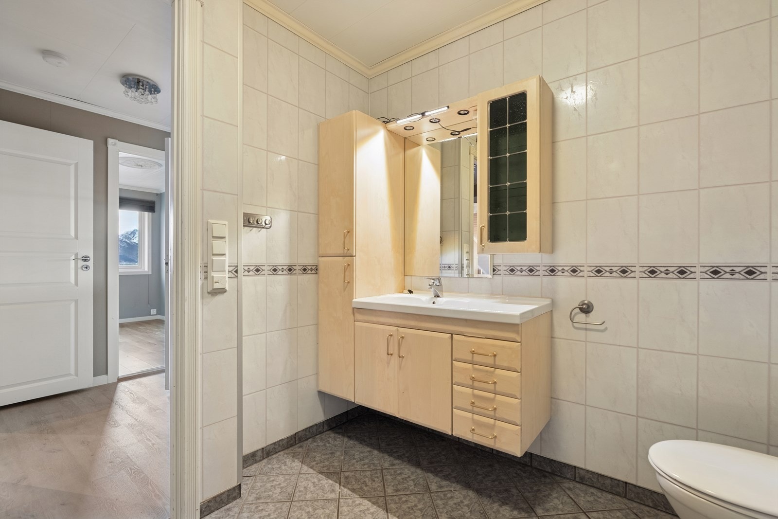 Baderomsinnredning med nedfelt servant og speilskap gir praktisk oppbevaring. Galleribilde