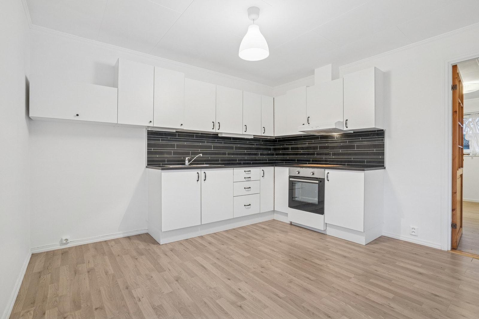 Innredningen har glatte fronter og laminat benkeplate med nedfelt benkebeslag i rustfritt stål med to kummer. Galleribilde