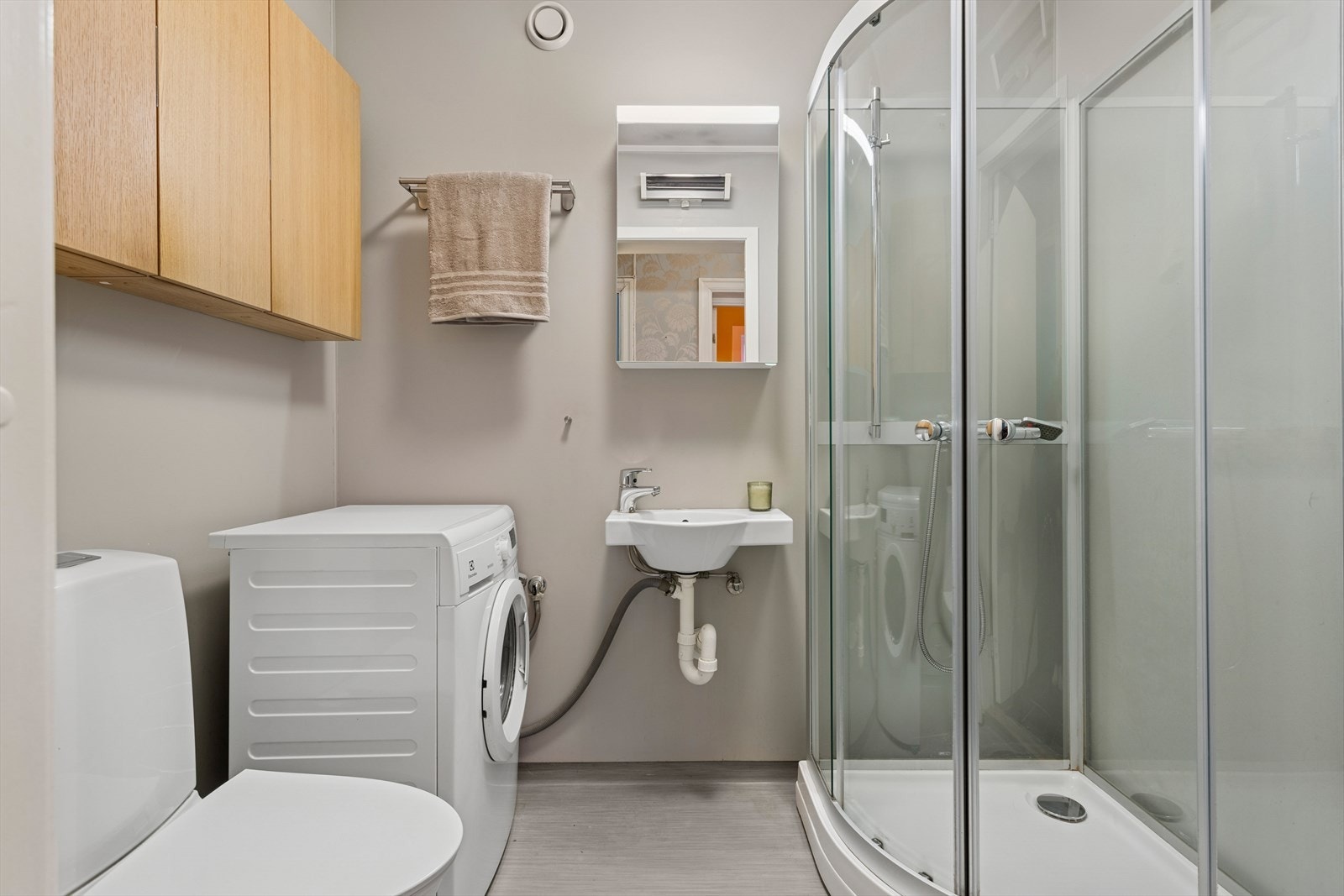 Badet består av skap med glatte fronter, speil over servant, servant, dusjkabinett og klosett. Galleribilde