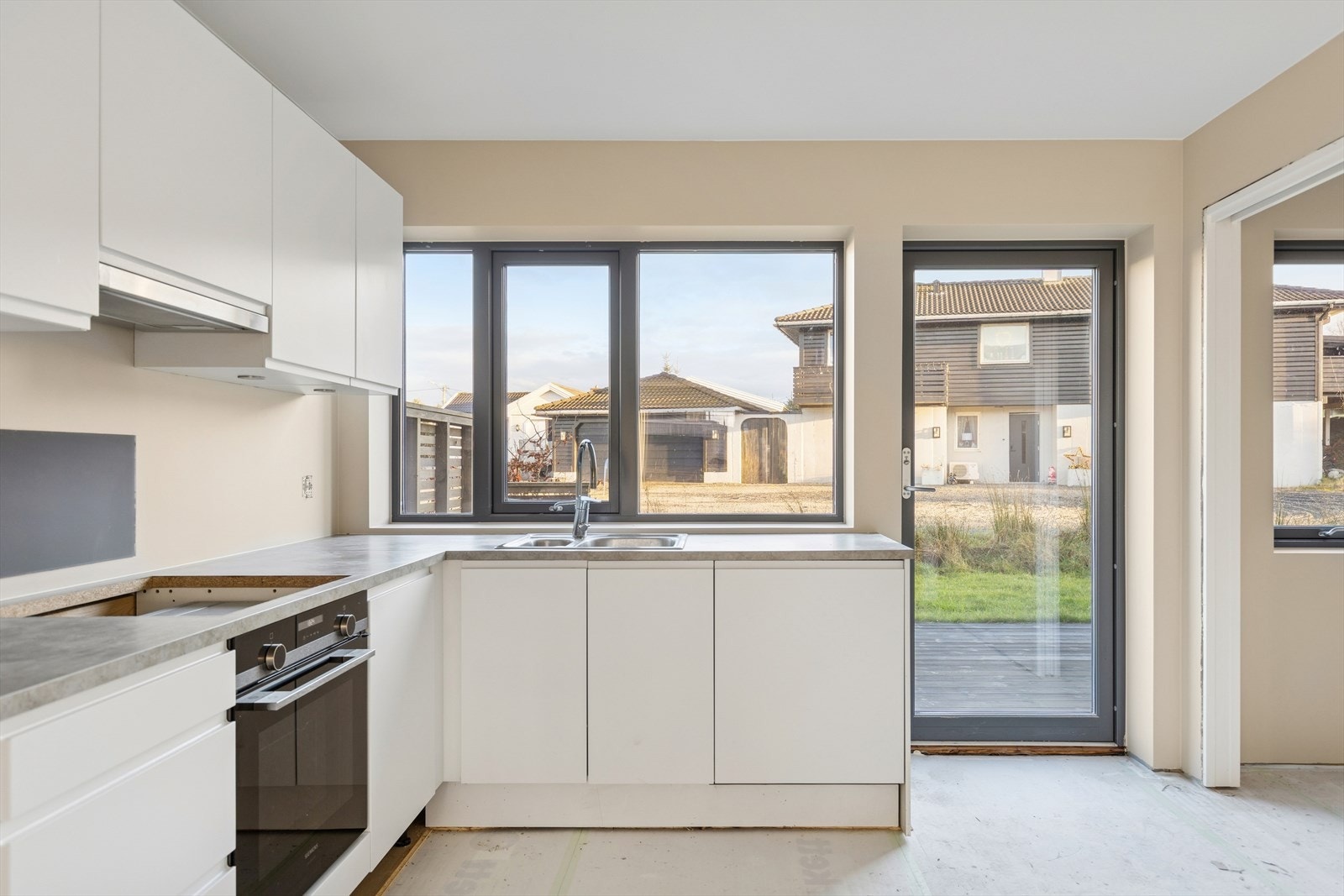 Lyst og moderne kjøkken med store vinduer som slipper inn rikelig med dagslys. En del arbeid gjenstår. Galleribilde