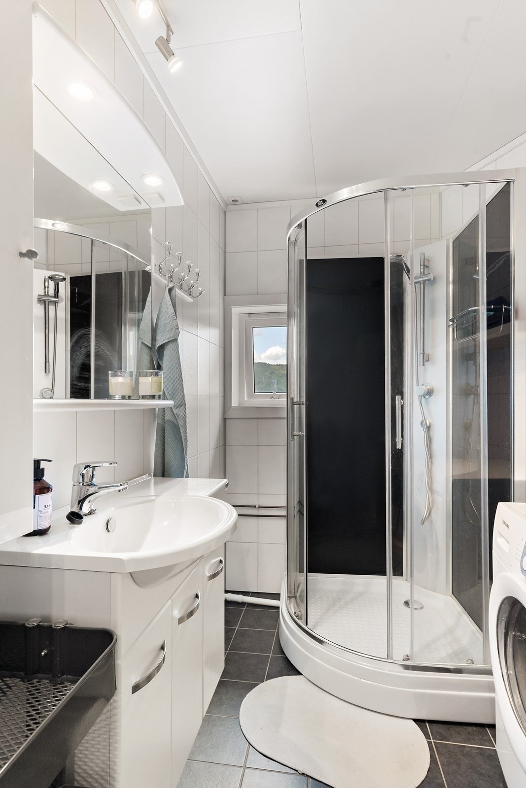 Badet har en tidløs stil med hvite våtromsplater på vegger og mørke flis på gulvet. Termostatstyrte varmekabler og flisegulv. Galleribilde