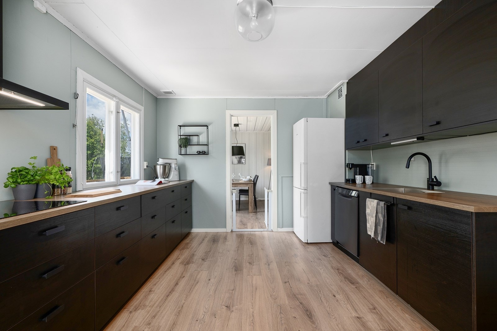 Pent og moderne kjøkken har innredning med svarte, glatte fronter. Integrerte hvitevarer. Galleribilde