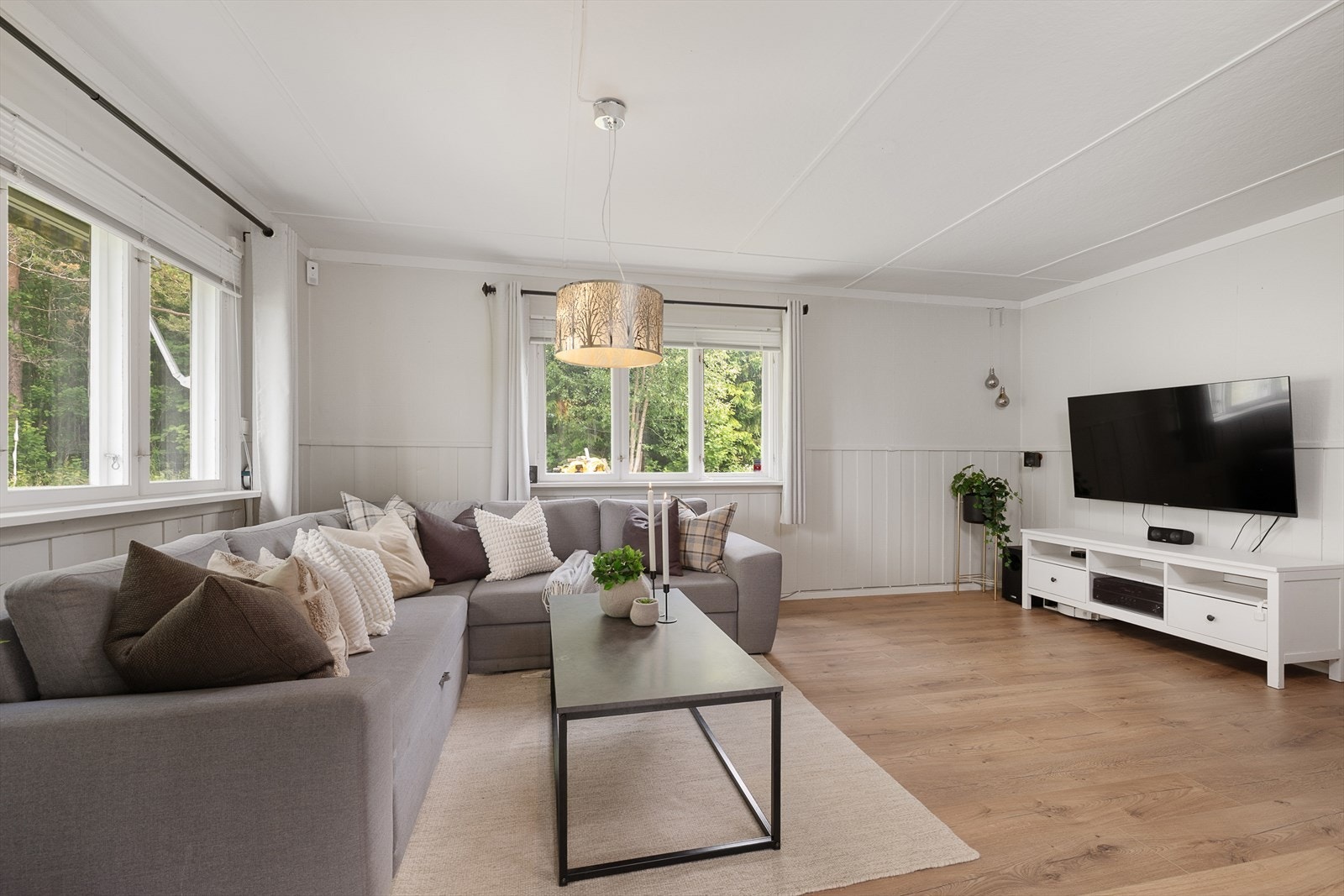 Hyggelig stue som får rikelig med naturlig lys inn i rommet gjennom vinduer på 2 vegger. Galleribilde