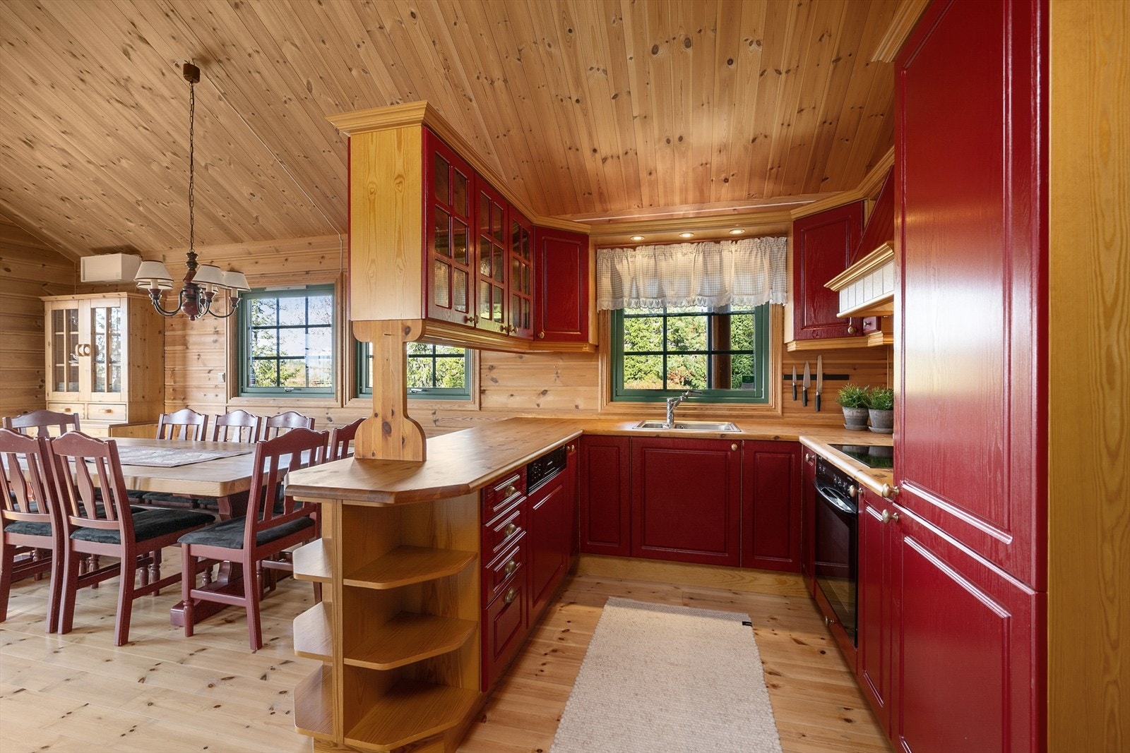 Kjøkkenet har innredning med rødmalte fronter. Det er godt med skap-og benkeplass. Integrerte hvitevarer. Galleribilde