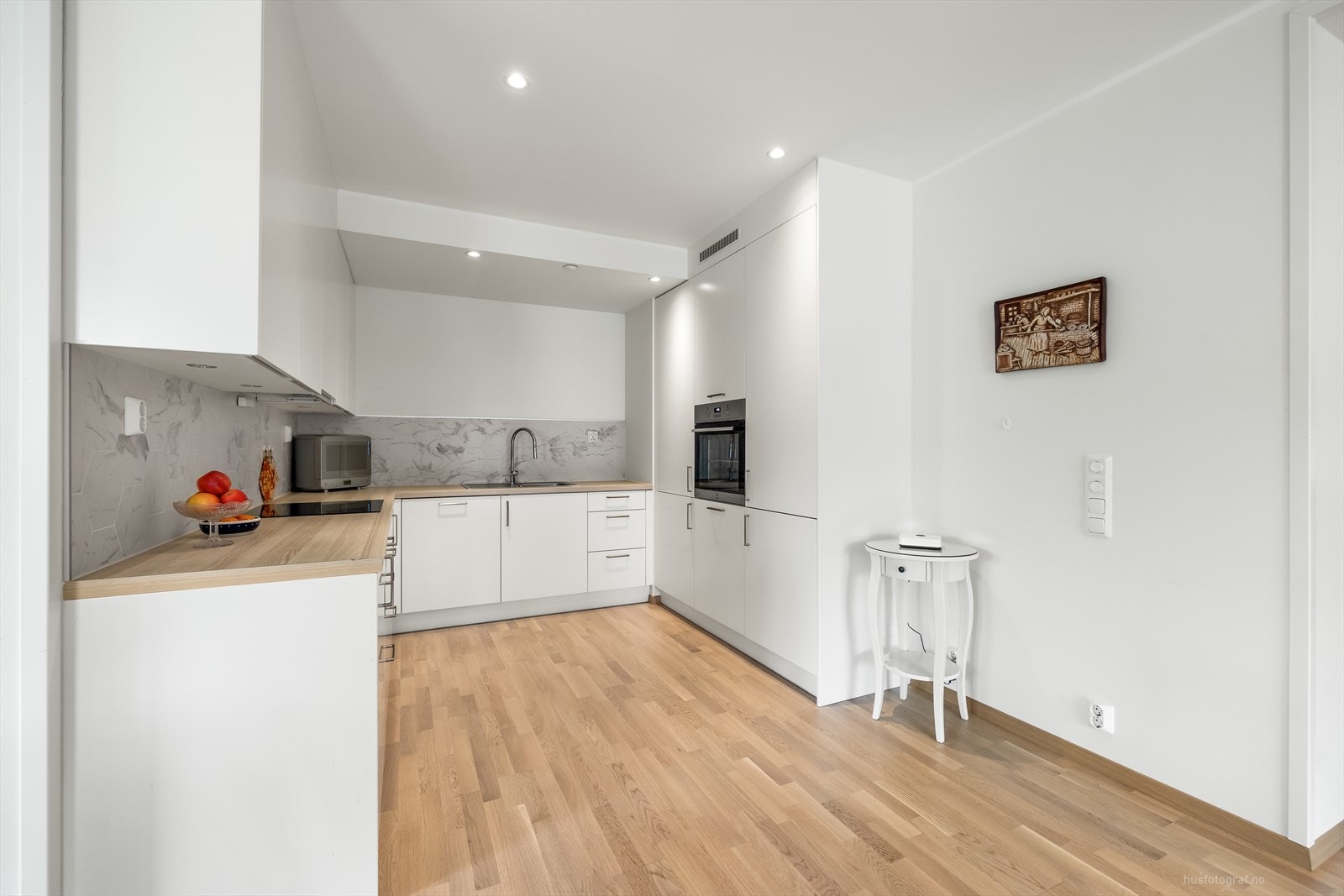 Romslig pent kjøkken med innredning med glatte fronter. Benkeplaten er av laminat. Galleribilde