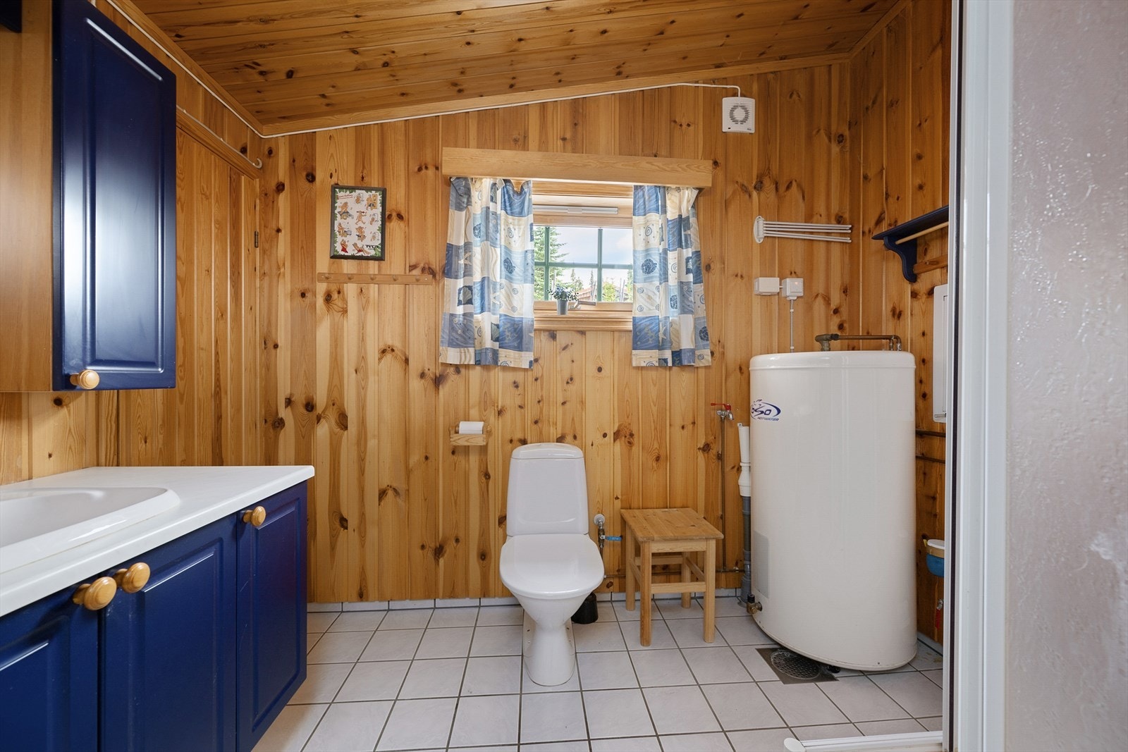 Badet har gulvmontert WC. Varmtvannsbereder plassert på badet. Dusjkabinett. Galleribilde