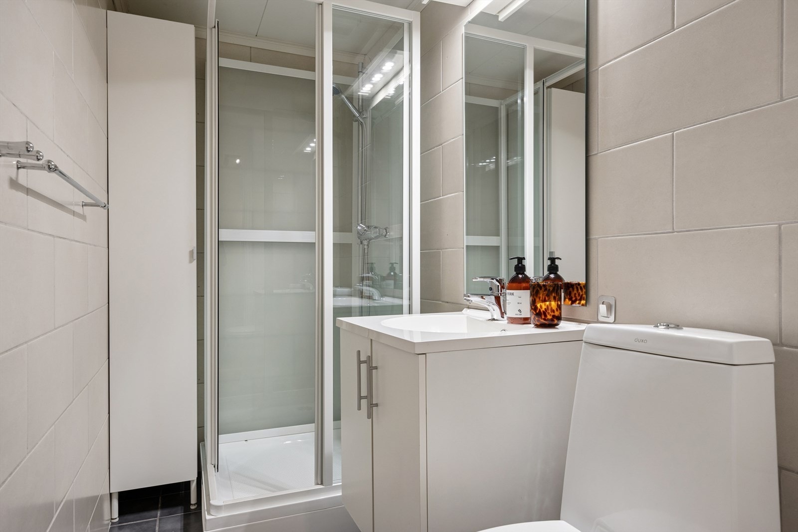 Svært pent flislagt baderom som er innredet med dusjkabinett, gulvmontert toalett og servant. Galleribilde