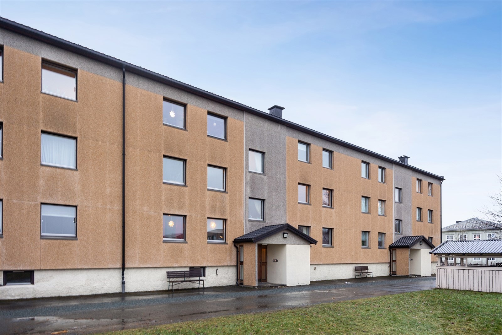 Fasade inngangsparti. Det er godt med parkeringsmuligheter i borettslaget. Felles utvendig sykkelparkering vises til høyre. Garasje og elbil lader etter ansiennitet. Galleribilde