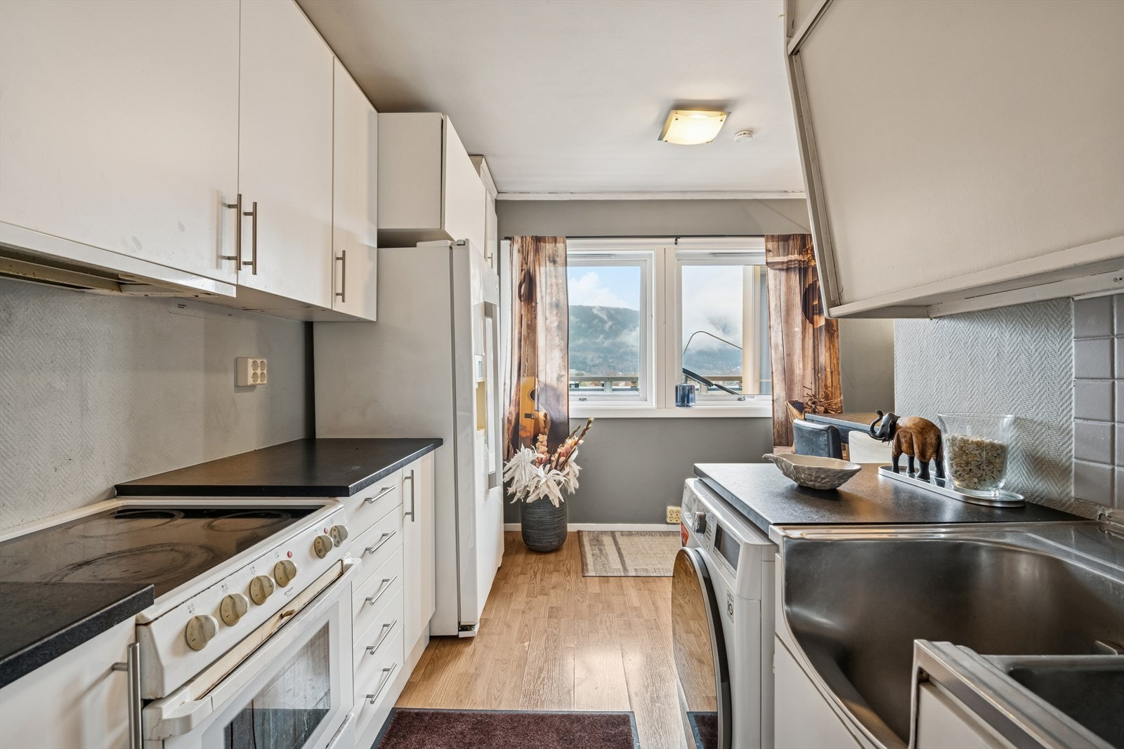 Her finner du en innredning med glatte fronter og benkeplate i laminat. Rommet har laminat på gulvet, malte strievegger og malt betong i taket. Galleribilde