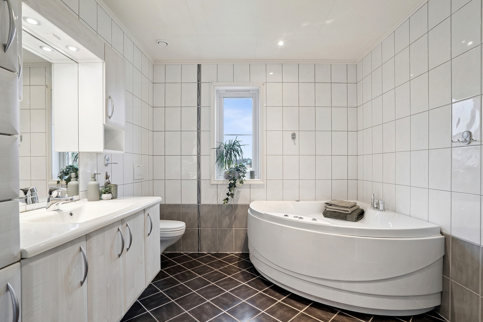 Romslig og flislagt baderom med herlig varme i gulv. Det er tidløs innredning med god oppbevaringsplass, samt downlights i himling. Galleribilde