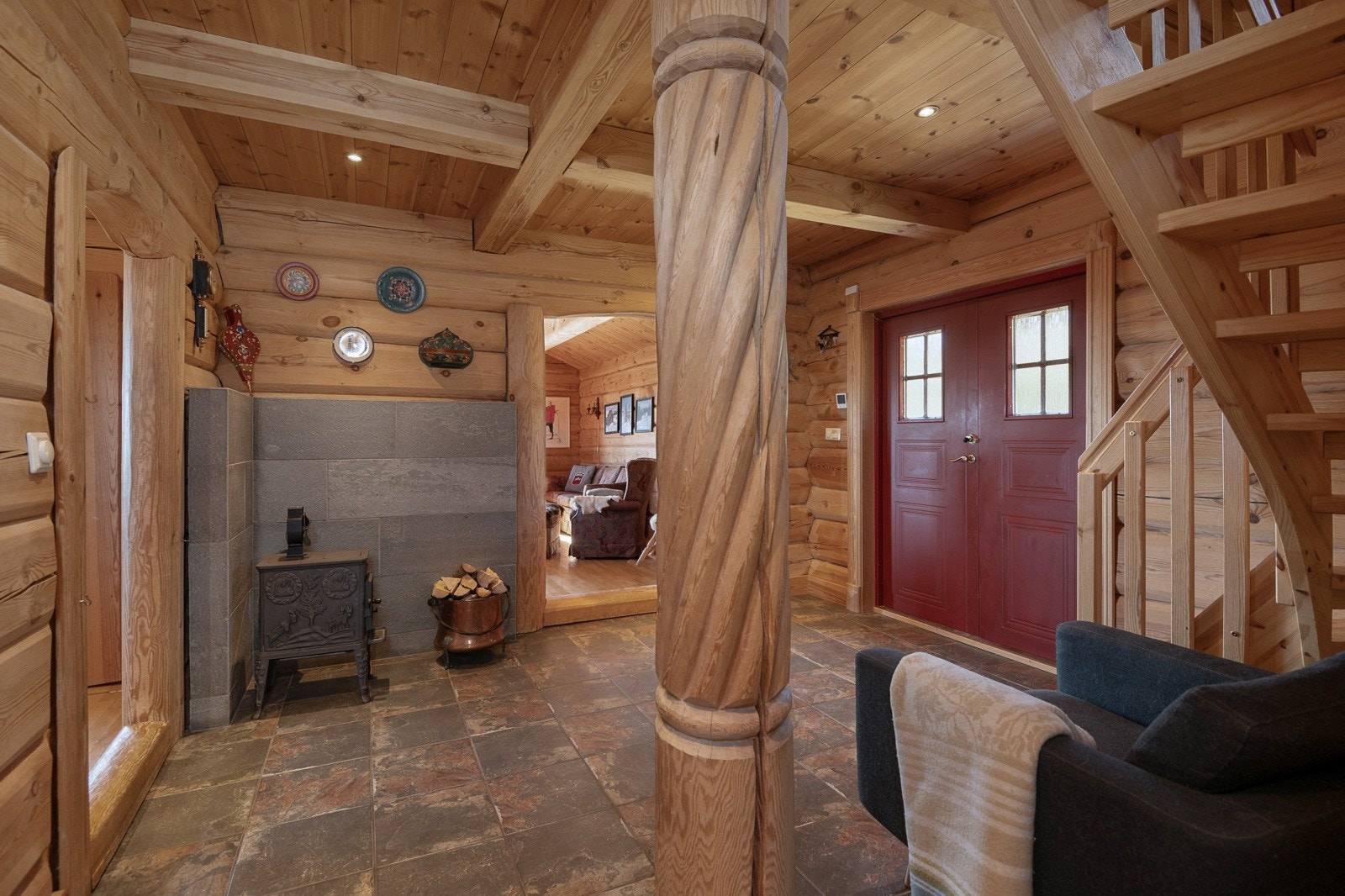 Velkommen inn - Her ønskes du velkommen inn i romslig hall. Hallen gir deg en innbydende velkomst gjennom den doble døren, med tømmer på vegger og fliselagte overflater på gulvet. Galleribilde