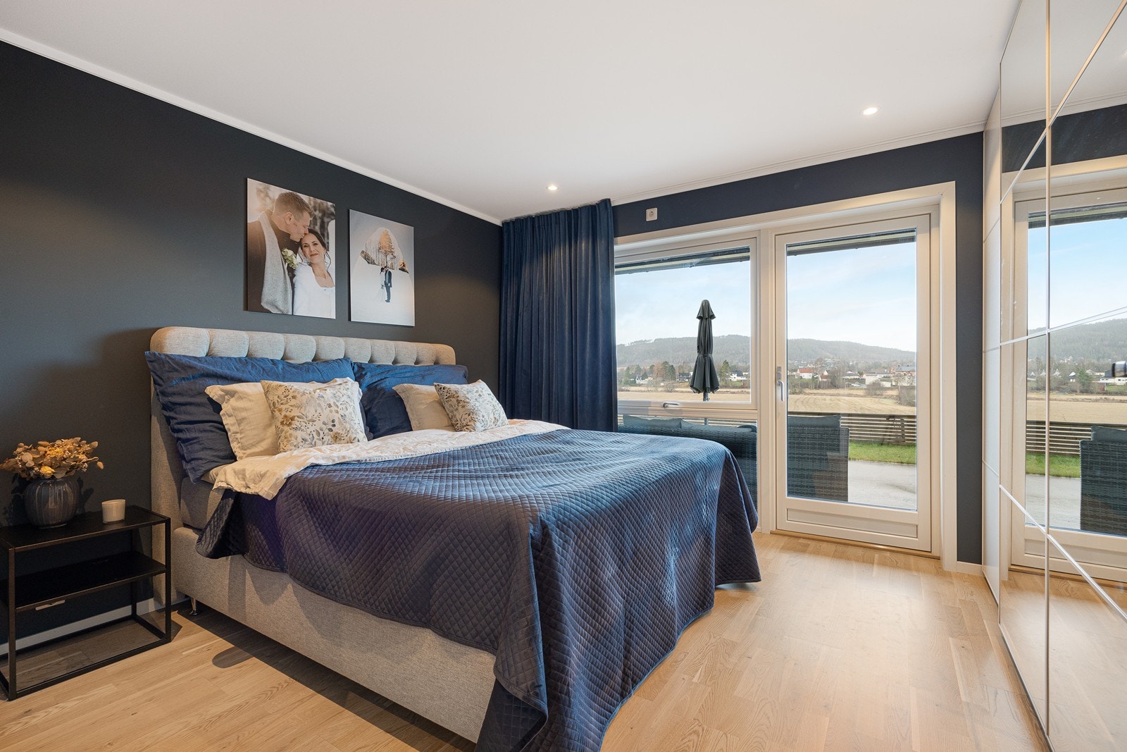 Hovedsoverommet er meget romslig, med downlights, parkettgulv og glassdør til terrassen. Veggene er malt i en mørk blåtone for en lun og avslappende atmosfære. Galleribilde