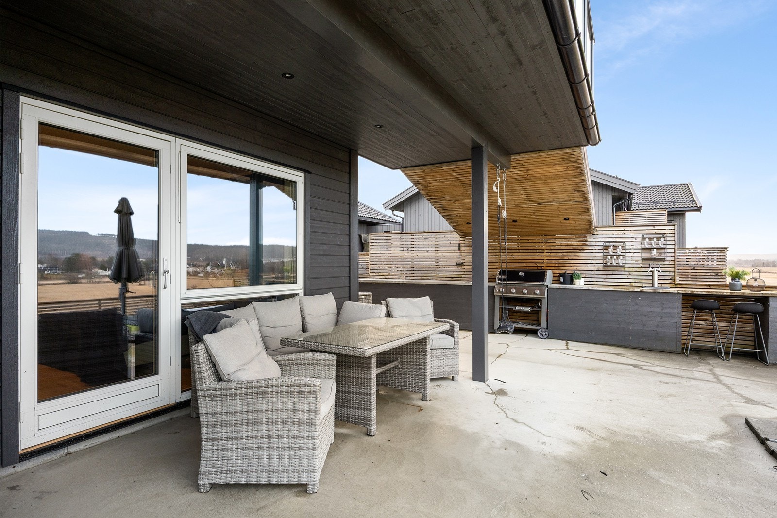 En stor spilevegg har tilhørende tak med downlights, tilknyttet et lite overbygg på terrassen. Også her er spotter installert, uteplassen har utestikk og annen belysning. Galleribilde