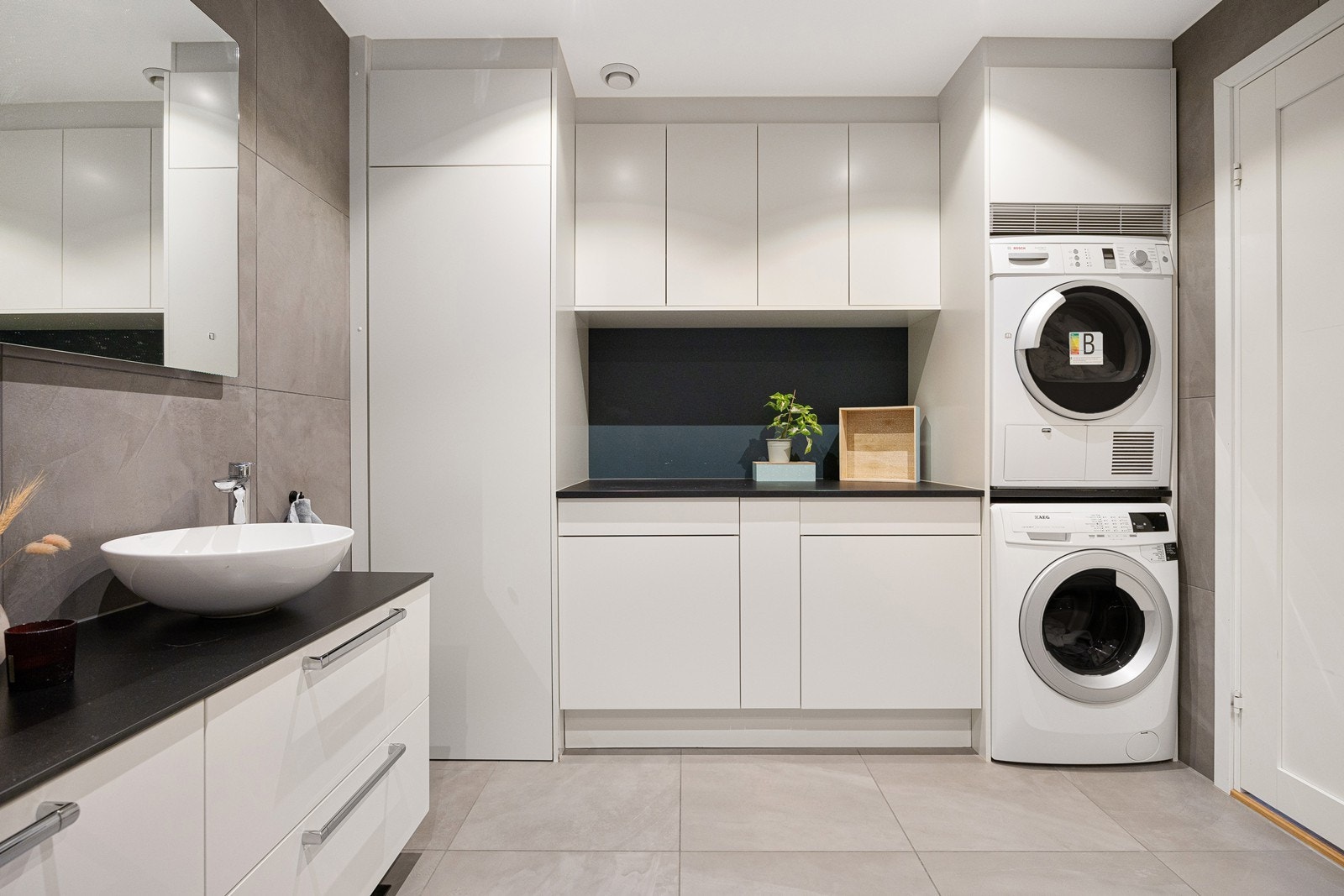 En egen vaskeromsdel er svært praktisk i hverdagen, bestående av et hvitt benkeskap med tilhørende vegg- og overskap. Integrert i innredningen er det opplegg for vaskemaskin og plass til tørketrommel. Galleribilde