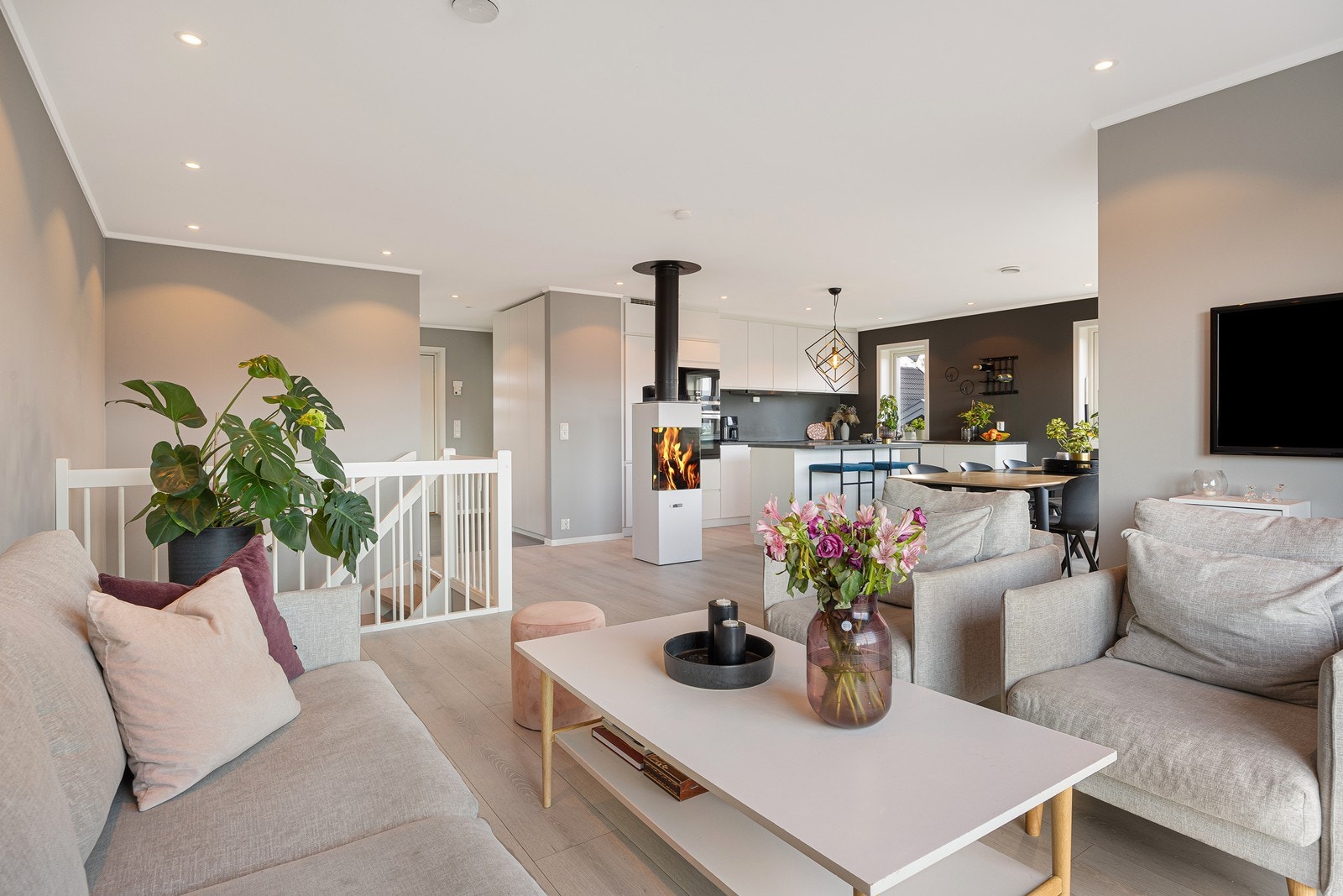 Sammen danner stuen og kjøkkenet et åpent, luftig og innbydende allrom. Gulvet har 1-stavs laminat i stilren utførelse, kombinert med veggflater malt i ulike grånyanser. Galleribilde