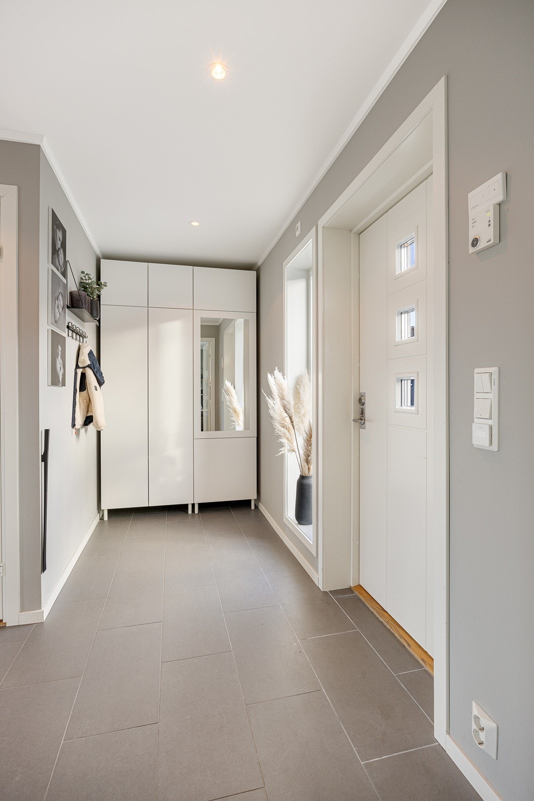 Entreen gir et godt førsteinntrykk, med downlights, varmekabler og store, grå fliser på gulvet. Galleribilde