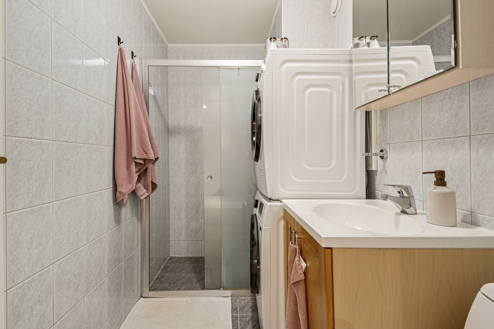 Badet er lyst og er utstyrt med dusjhjørne, gulvstående toalett og opplegg for både vaskemaskin og tørketrommel. Galleribilde