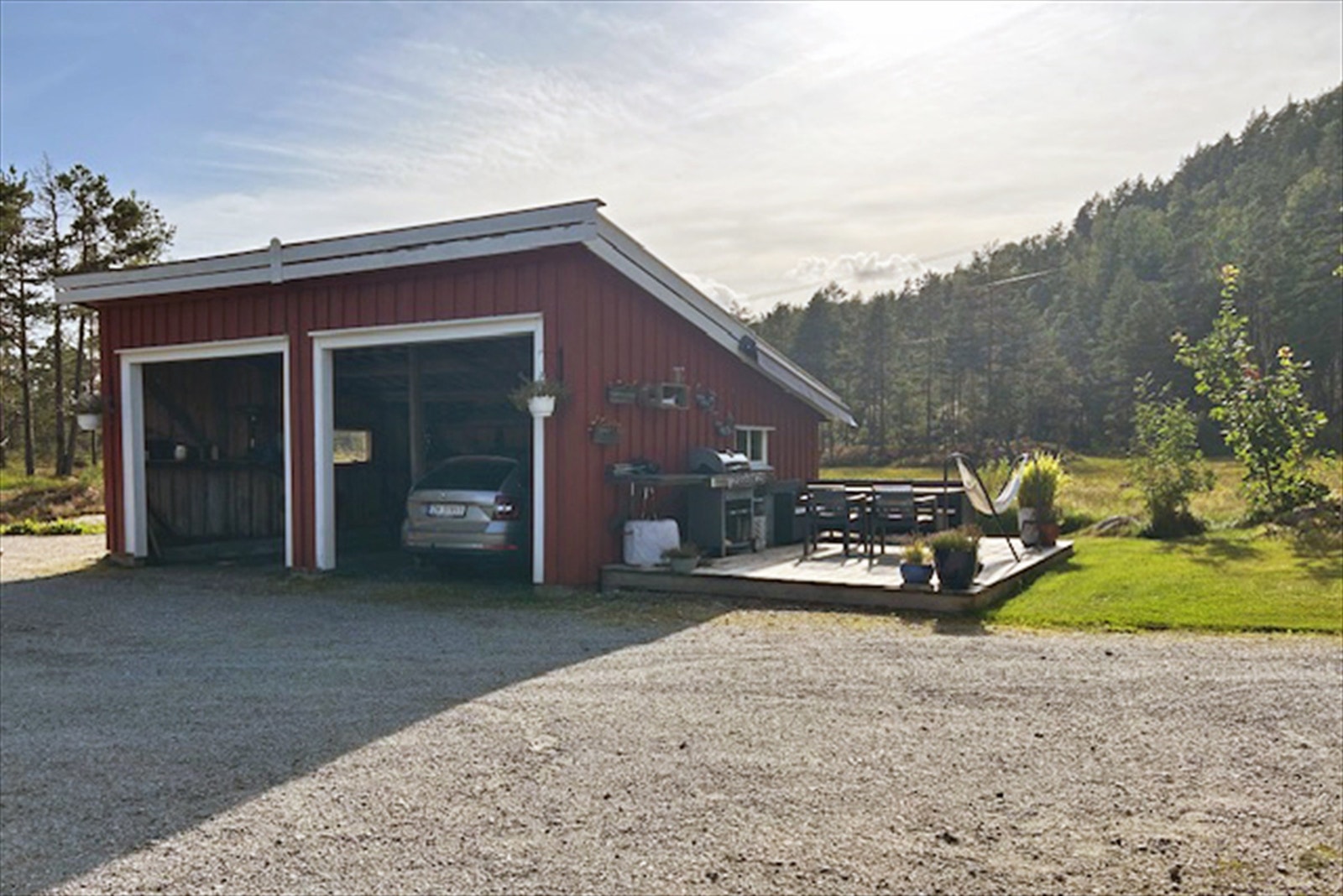 Dobbelt garasje med lun solrik uteplass på siden. Galleribilde