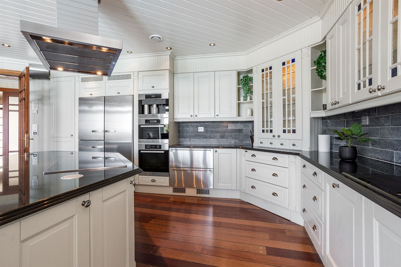 Innredning av eik med lekre detaljer. Her er det kjølskuffer og integrert koketopp, kaffemaskin, dampovn, stekeovn, kjølesekap, fryser, vinskap og oppvaskmaskin Galleribilde