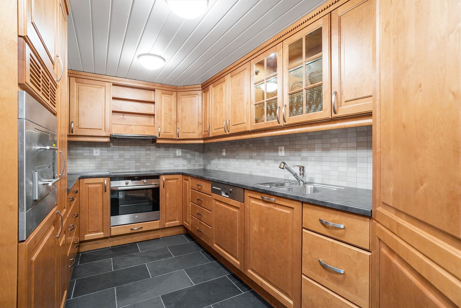 Eget kjøkken i underetasjen med integrerte hvitevarer og kjølehjørne Galleribilde