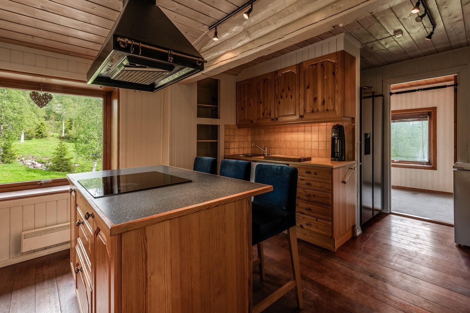 Koselig kjøkkenøy med nedfelt koketopp, ventilator og sitteplasser rundt. Galleribilde