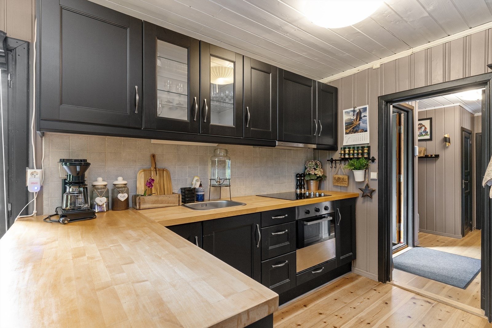 Stue/kjøkken består av trepanel på vegger og himling og har tregulv. Mellom over - og benkeskap ved kjøkken er det fliselagt. Galleribilde