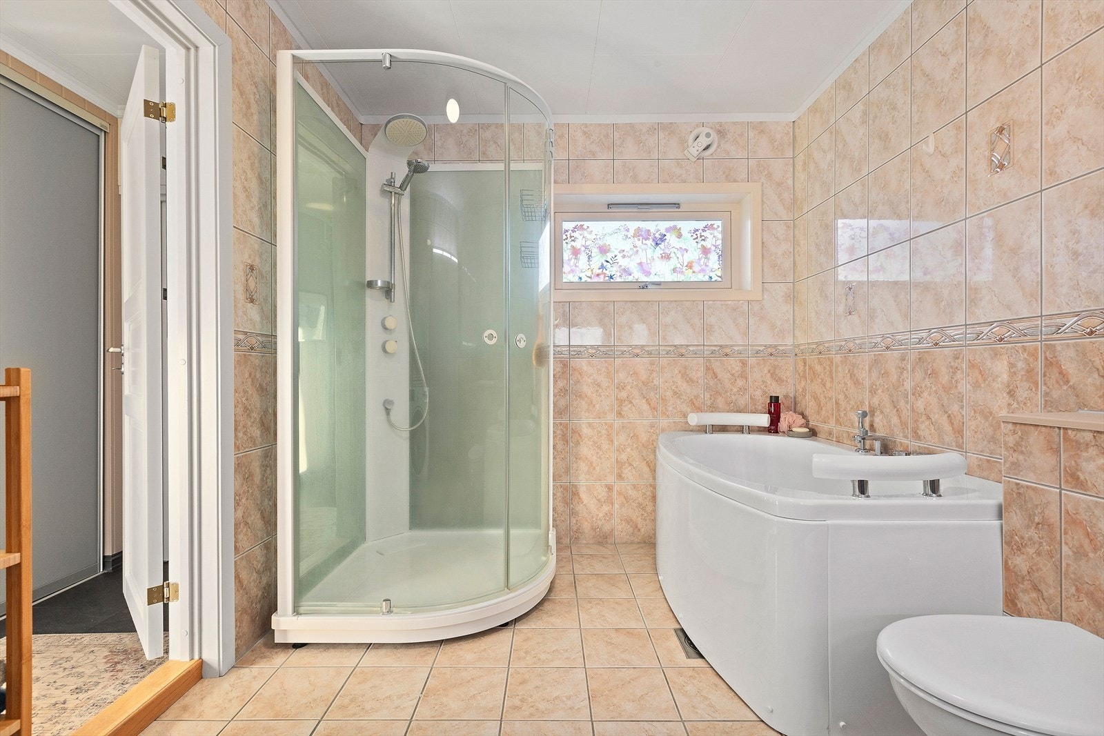 Rommet er innredet med to nedfelte servanter, veggmontert toalett, dusjkabinett og badekar. Galleribilde