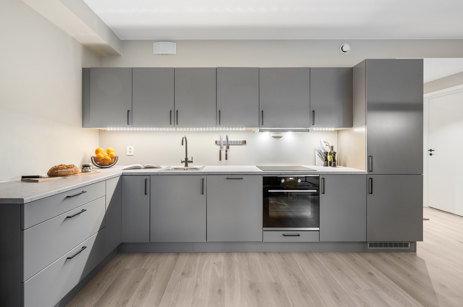 Kjøkkenet har stilrene grå fronter, integrerte hvitevarer og god benkeplass. Galleribilde