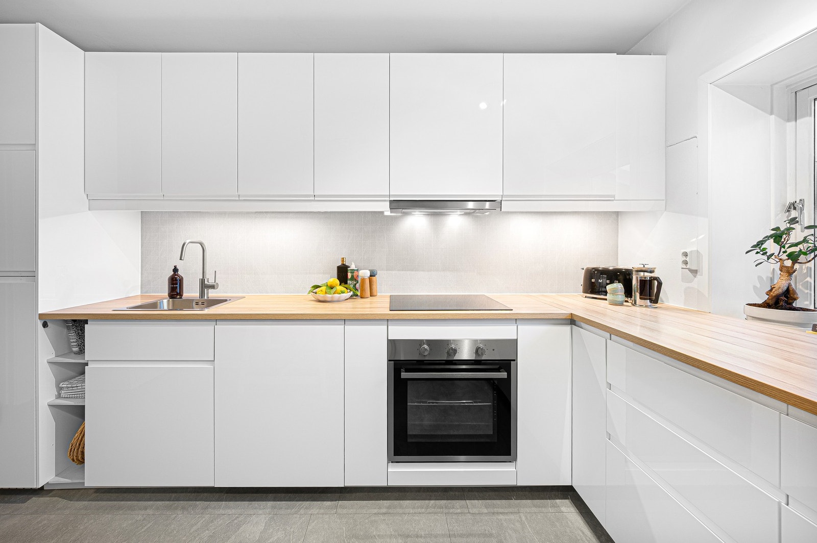 Kjøkkenet inneholder integrerte hvitevarer som platetopp, stekeovn, oppvaskmaskin og kjøleskap. Galleribilde