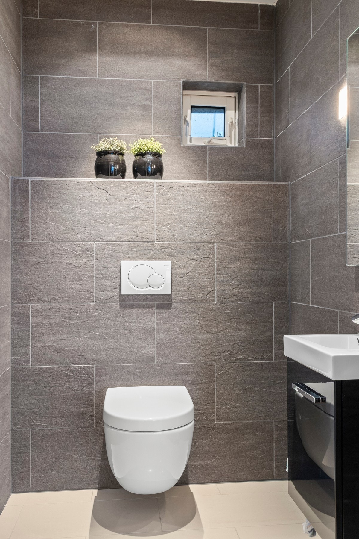 Toalettrom med behagelig gulvvarme som er utstyrt med veggmontert toalett og servantskap med servant. Galleribilde