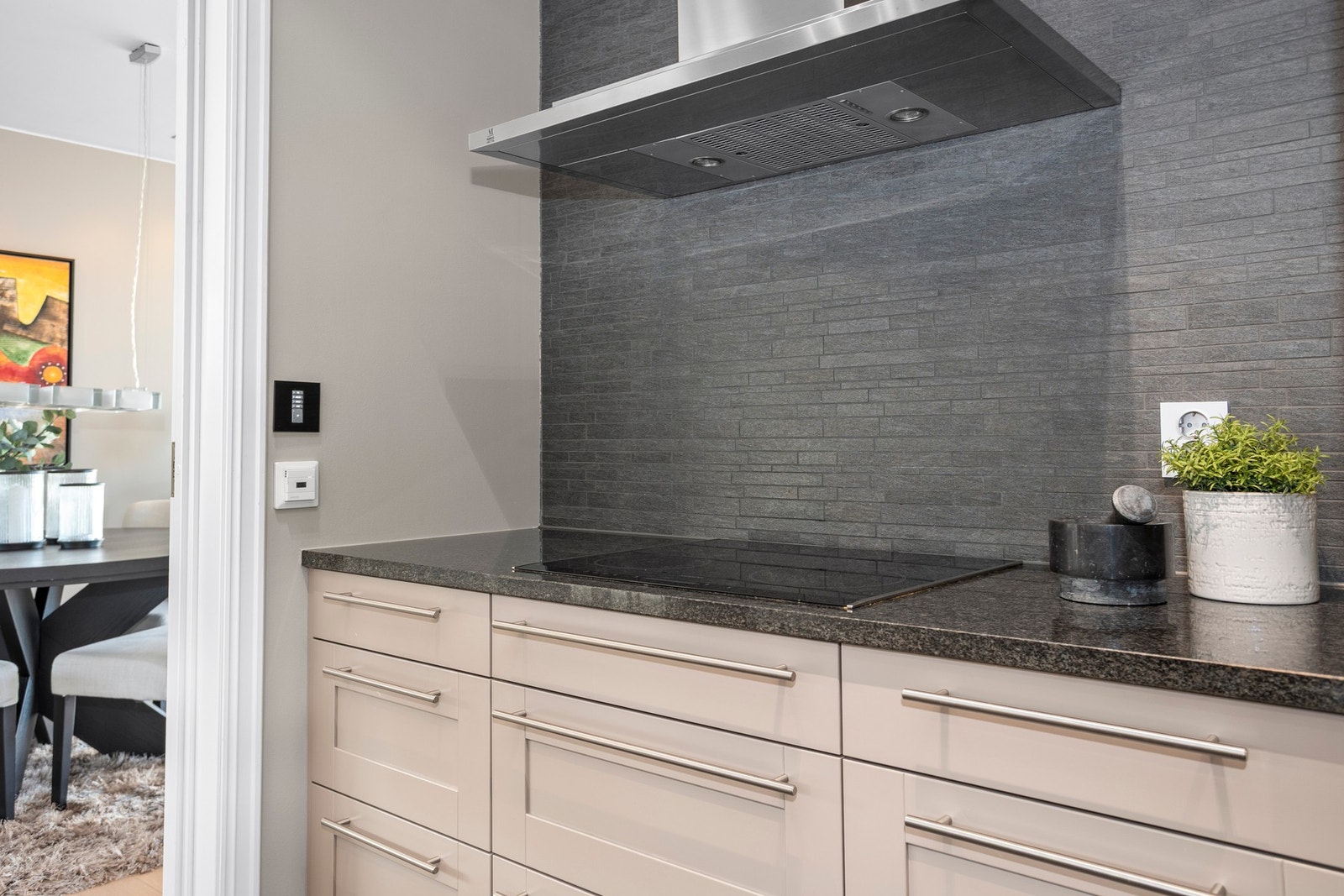 Det er mekanisk avtrekksvifte over stekesonen. Spotter og høyttalere i himling, parkett på gulv og malt overflate med flis over benkeplate. Galleribilde