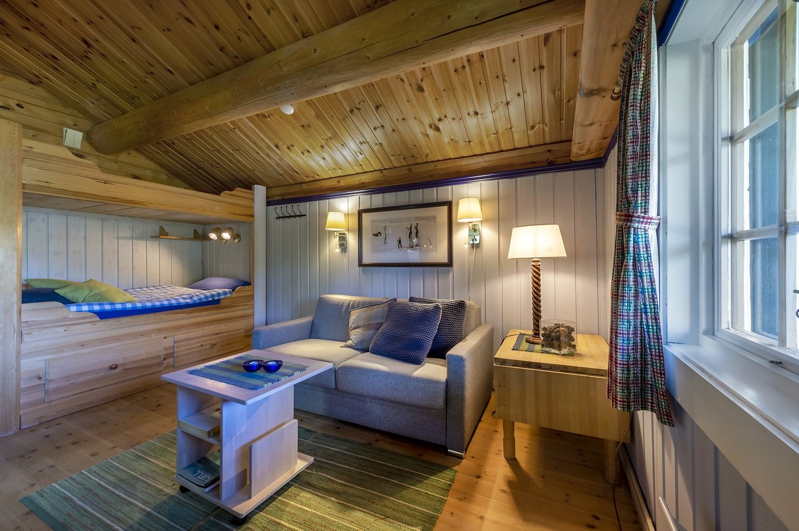 Rommet har bred, plassbygget køye med skuffer og skap Galleribilde