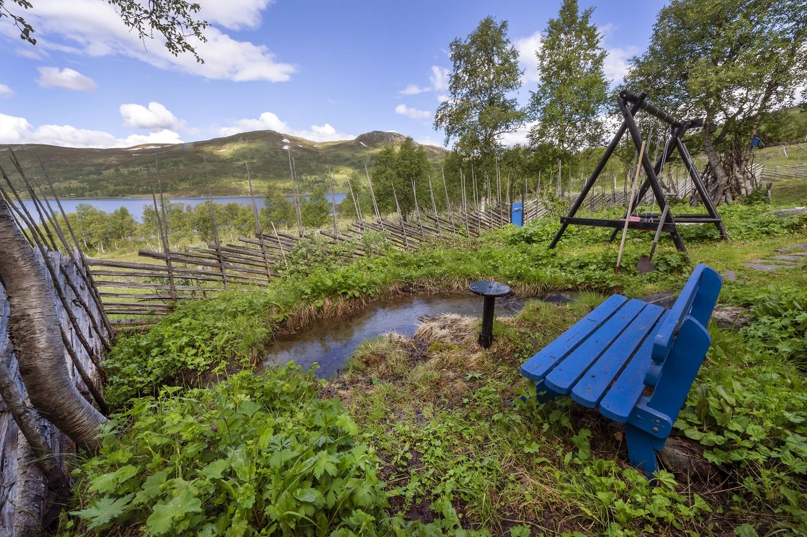 Et lite miljø med dam og huskestativ nedenfor hytta Galleribilde
