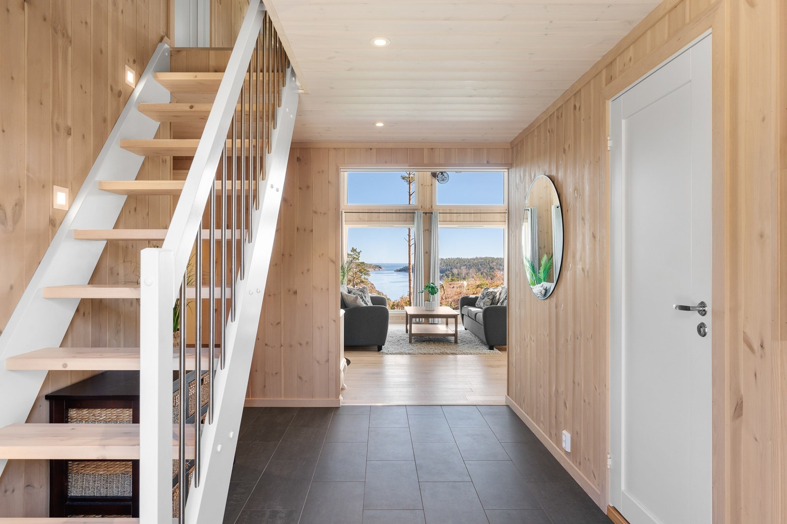 Romslig gang med flislagt gulv. Stuen med de store vindusflatene rett frem i det man kommer inn gir et innbydende førsteinntrykk Galleribilde