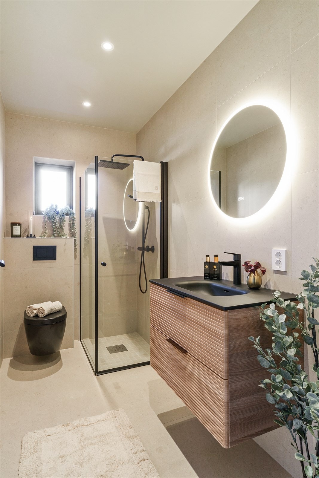 Bad i 1.etasje. Badet er fliselagt med store fliser både på gulv og vegger, med en kontrast i dusjsone på gulv hvor det er mindre fliser som gir et delikat og moderne uttrykk. Galleribilde