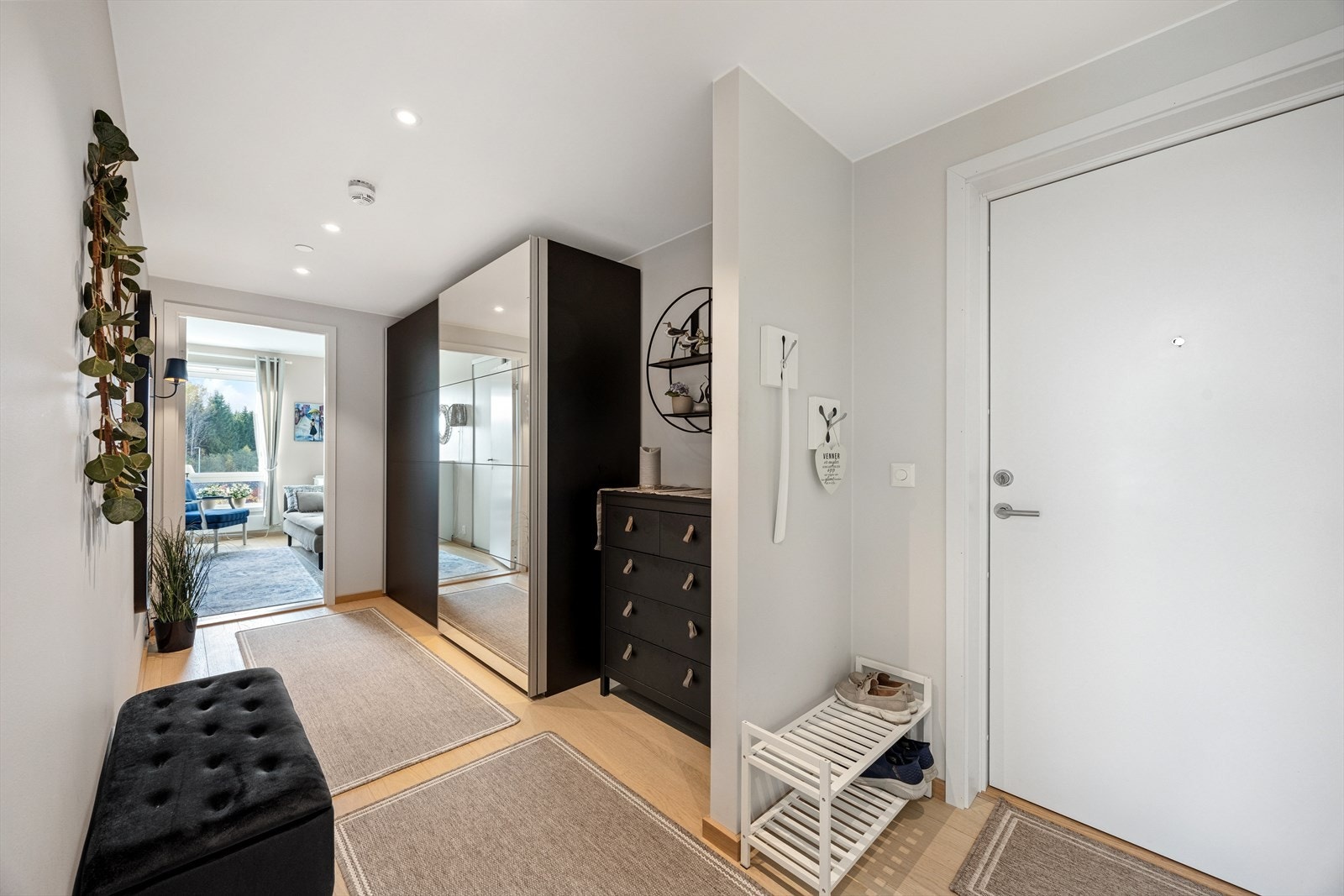 Vel innenfor døren til leiligheten blir du møtt av en romslig og lekker entré/gang med parkett på gulvet. Her er det installert en stor skyvedørsgarderobe for praktisk oppbevaring. Galleribilde