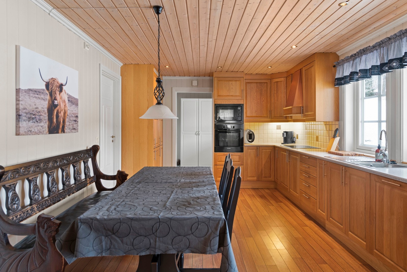 Kjøkkenet er fra byggeår og har eikefronter, laminat benkeplate, induskjonstopp med kobberhette, integrerte hvitevarer og god skapplass Galleribilde