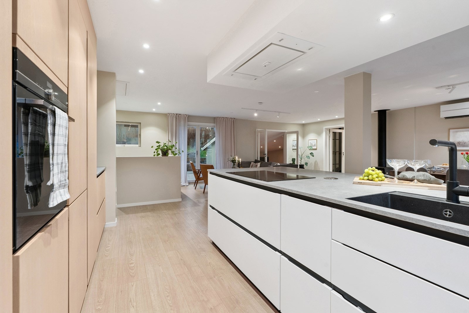 Hvitevarer som koketopp, stekeovn, oppvaskmaskin og kombiskap (kjøl og frys) er sømløst tilpasset innredningen. Over koketoppen er det ventilator integrert i taket, en moderne og elegant løsning Galleribilde