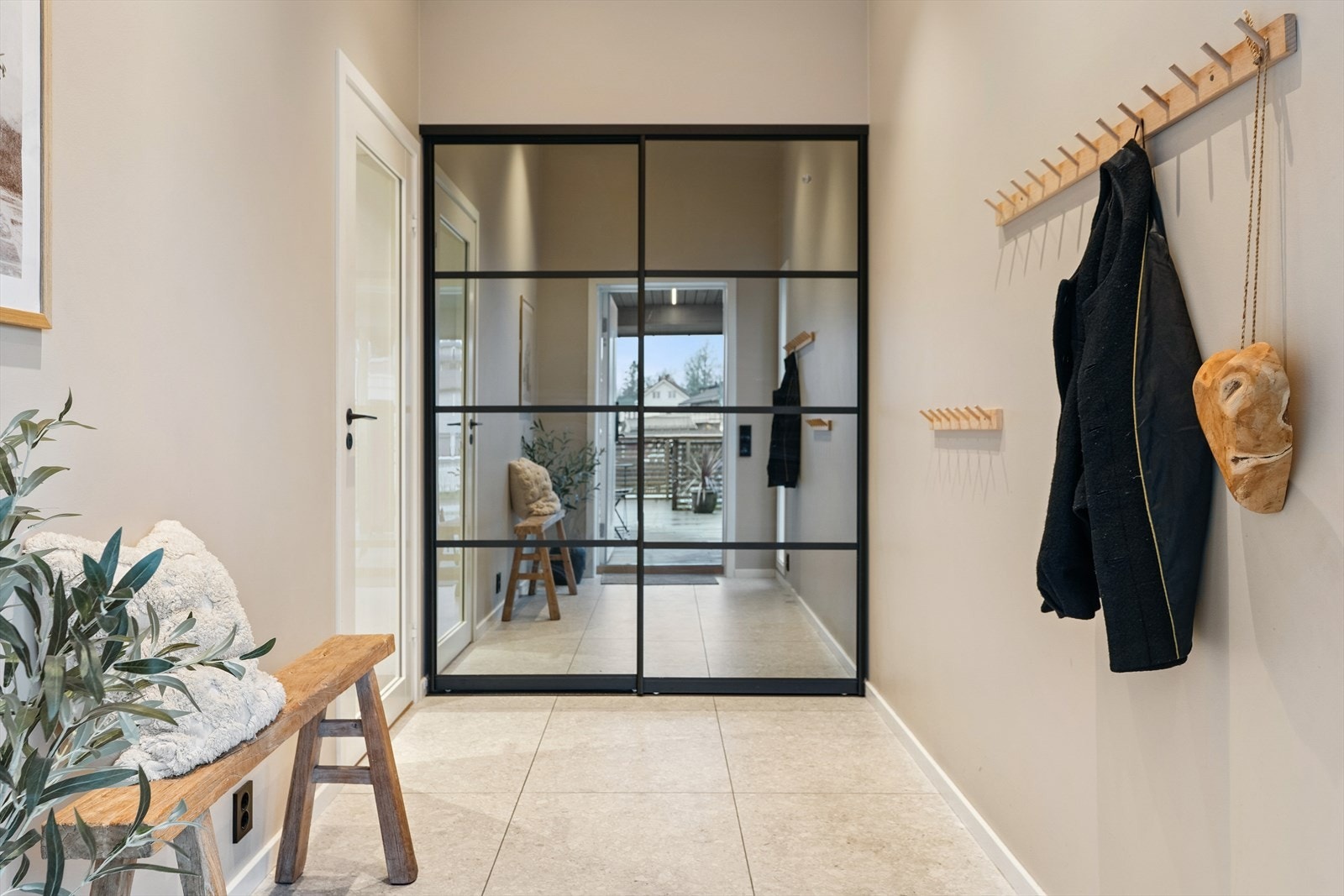 Innenfor døren møtes du av en romslig og lys gang med god plass til både sko og yttertøy i en lekker skyvedørsgarderobe med speilfronter og sorte detaljer Galleribilde