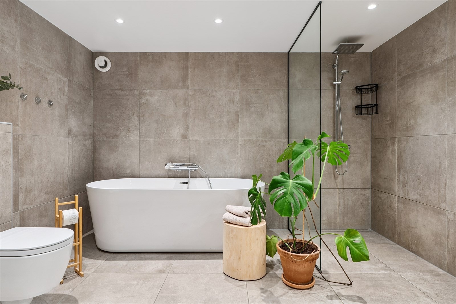 Badet er utstyrt med vegghengt toalett, badekar og et romslig dusjhjørne med dusjvegg i herdet glass Galleribilde