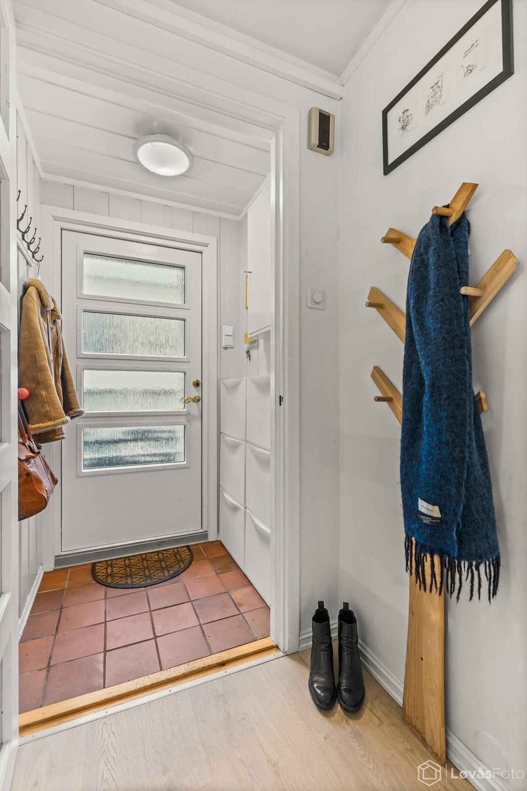 Du ønskes velkommen inn i en entré med slitesterkt flisgulv og malt trepanel. Galleribilde