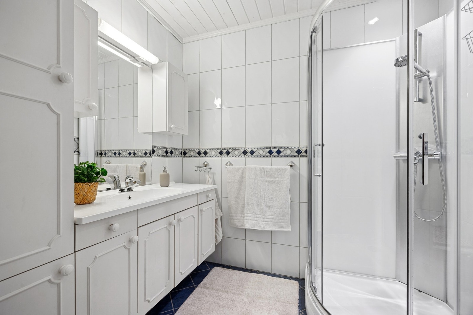 Badet har mekanisk avtrekksvifte og er innredet med vegghengt servantinnredning, speil med integrert belysning, dusjkabinett og vegghengt toalett. Galleribilde